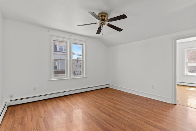 spare room featuring baseboard heating, wood finished floors, healthy amount of natural light, lofted ceiling, and a ceiling fan
