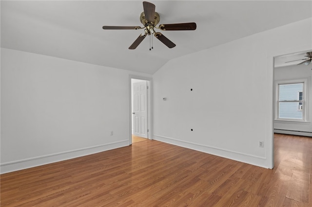 spare room featuring vaulted ceiling, light wood-type flooring, a ceiling fan, baseboards, and a baseboard heating unit