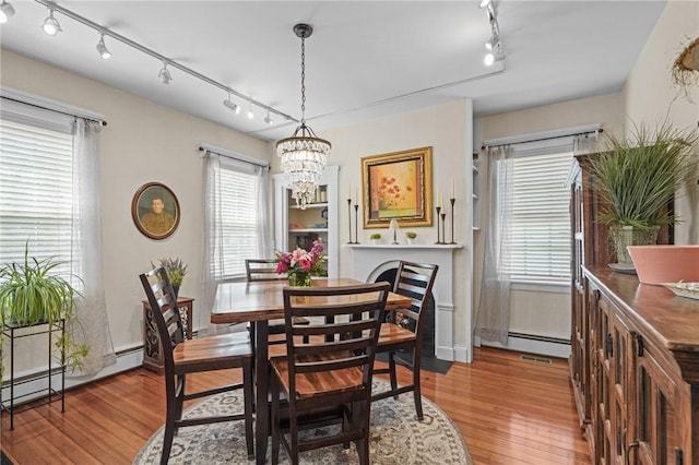 275 Hope St, Bristol, RI 02809 - dining space with track lighting, a chandelier, wood finished floors, and a baseboard radiator