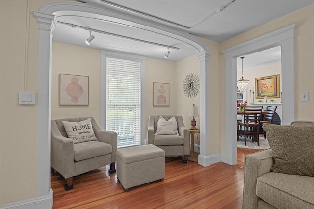 275 Hope St, Bristol, RI 02809 - sitting room featuring track lighting, decorative columns, wood finished floors, and a chandelier
