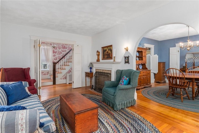 35 Miles Ave, East Providence, RI 02914 - living room featuring light wood finished floors, arched walkways, stairs, a chandelier, and a brick fireplace