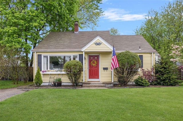 view of front of home with a front yard, a chimney, and roof with shingles