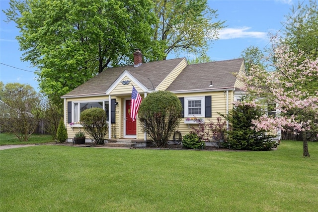view of front facade featuring a front yard, a chimney, and a shingled roof