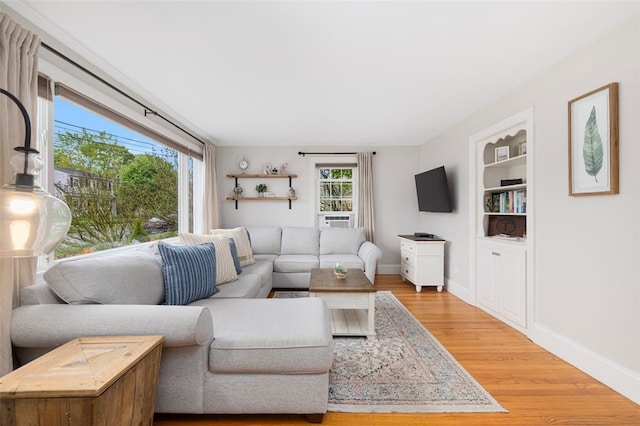 living area featuring wood finished floors, baseboards, and built in shelves
