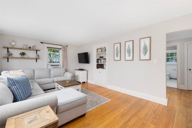 living room featuring light wood finished floors, baseboards, and built in features