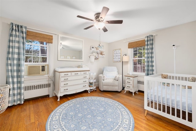 bedroom featuring radiator heating unit, wood finished floors, and a crib