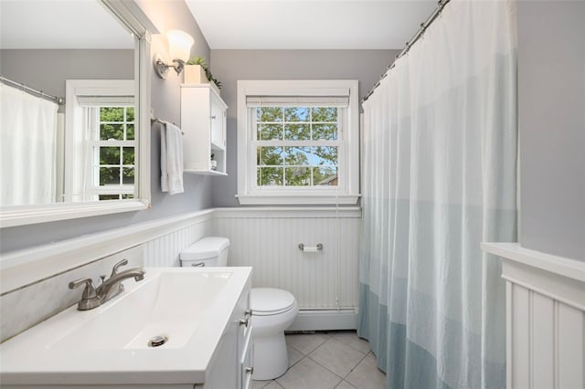 full bathroom with tile patterned flooring, toilet, plenty of natural light, a wainscoted wall, and vanity