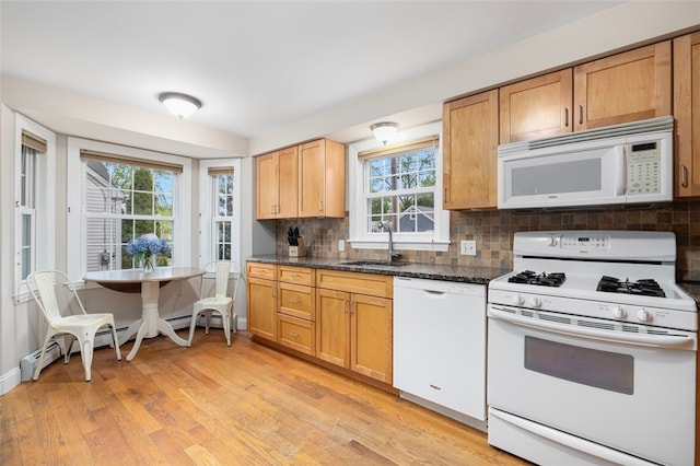 kitchen featuring white appliances, a sink, plenty of natural light, and light wood-style floors