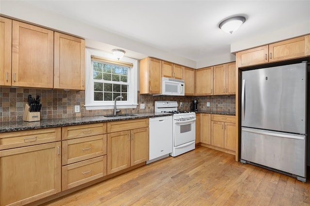 kitchen featuring white appliances, a sink, light brown cabinets, and light wood-style flooring