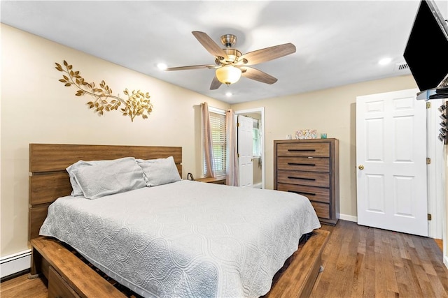 bedroom with a baseboard heating unit, wood finished floors, recessed lighting, a ceiling fan, and baseboards