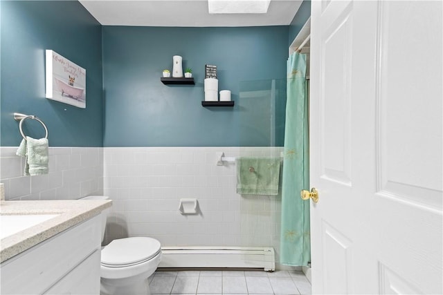 bathroom featuring baseboard heating, tile patterned flooring, tile walls, vanity, and toilet