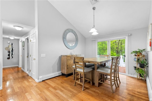dining space featuring a baseboard heating unit, light wood-style floors, vaulted ceiling, and baseboards