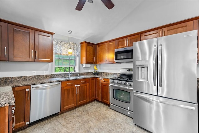 kitchen featuring stainless steel appliances, a sink, ceiling fan, vaulted ceiling, and brown cabinetry