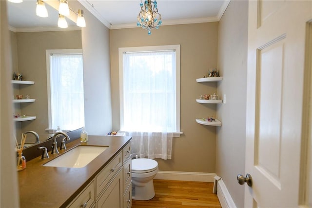 bathroom with wood finished floors, toilet, vanity, ornamental molding, and baseboards