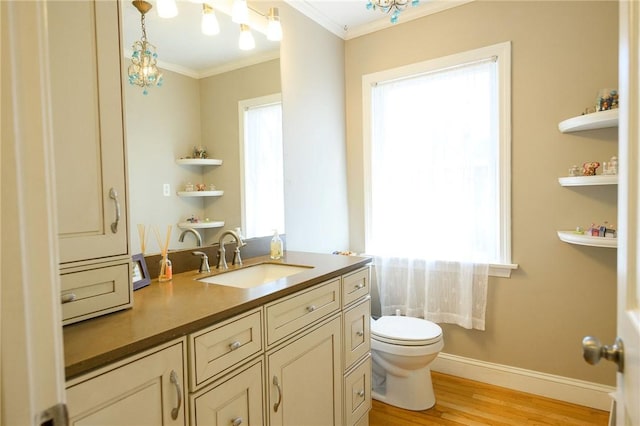 bathroom with ornamental molding, wood finished floors, plenty of natural light, toilet, and vanity