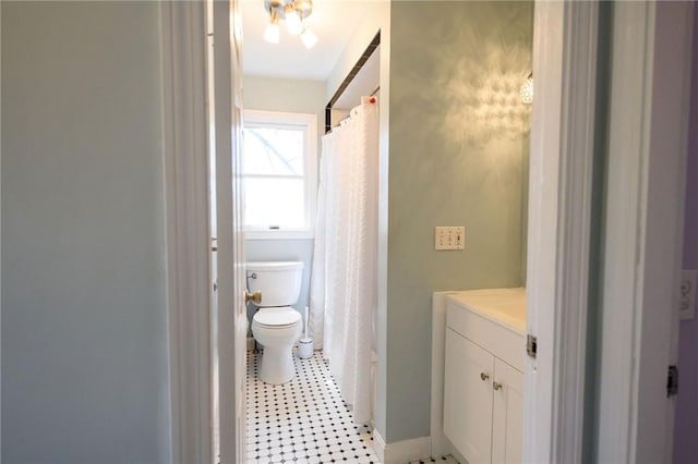 bathroom featuring toilet, vanity, baseboards, and a shower with shower curtain