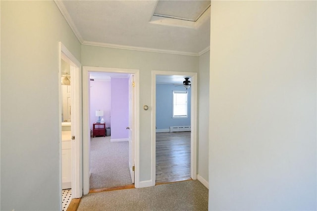 hall featuring a baseboard heating unit, crown molding, carpet, baseboards, and attic access