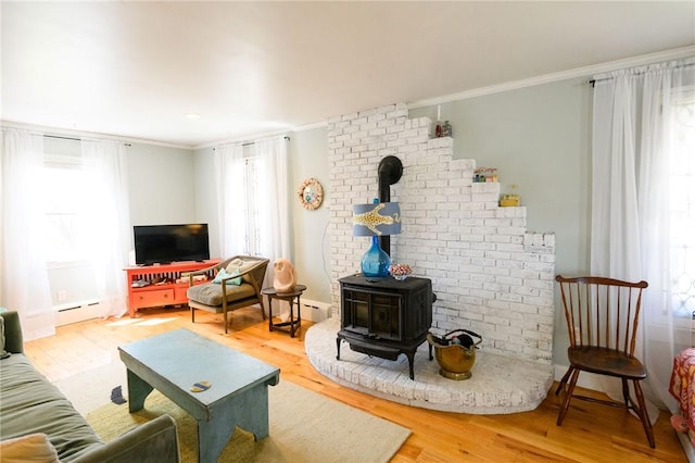 living area featuring ornamental molding, wood finished floors, a baseboard heating unit, and a wood stove