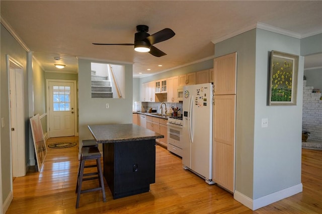 kitchen featuring white appliances, crown molding, a sink, light wood-style flooring, and light brown cabinetry