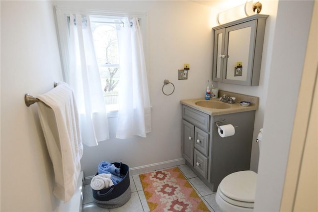 half bath with toilet, vanity, tile patterned floors, and baseboards