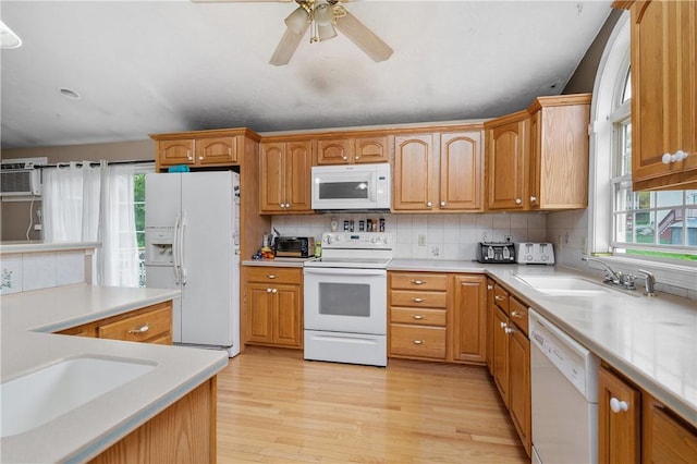 kitchen with white appliances, healthy amount of natural light, a sink, and light wood-type flooring