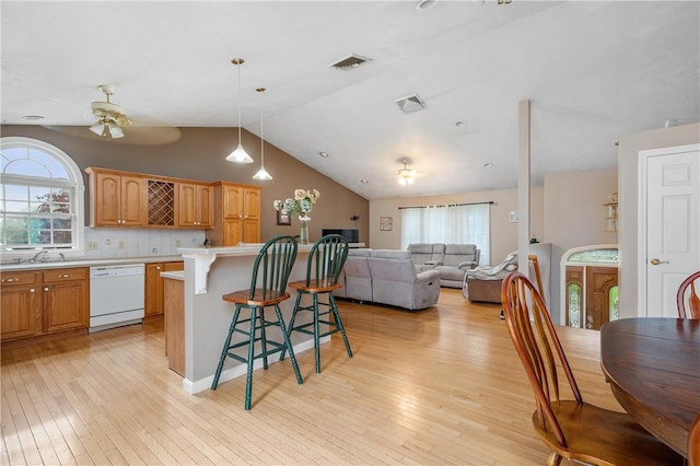 kitchen with white dishwasher, a breakfast bar area, ceiling fan, lofted ceiling, and light countertops