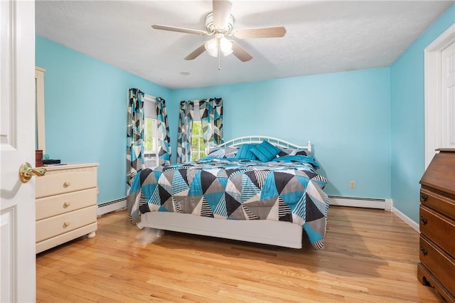bedroom with baseboard heating, wood finished floors, and a ceiling fan