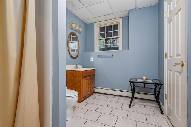 bathroom featuring a drop ceiling, vanity, a baseboard radiator, toilet, and tile patterned flooring