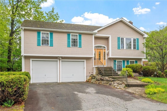 bi-level home featuring an attached garage, driveway, and a chimney