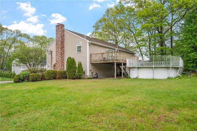 rear view of house with a wooden deck, a chimney, and a lawn