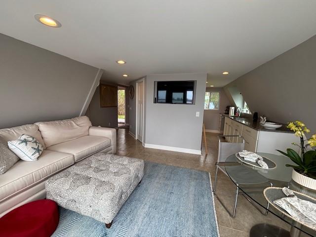 living room featuring recessed lighting, lofted ceiling, and baseboards