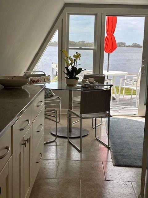 dining space with stone tile flooring and a water view