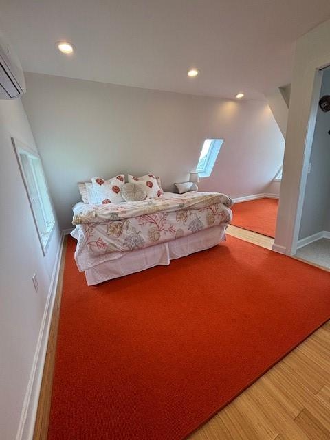 bedroom with a wall mounted air conditioner, recessed lighting, baseboards, light wood finished floors, and light carpet