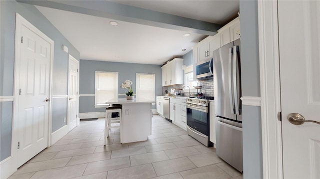 11 Crane St S, Pawtucket, RI 02860 - kitchen with appliances with stainless steel finishes, a breakfast bar, a sink, decorative backsplash, and white cabinets