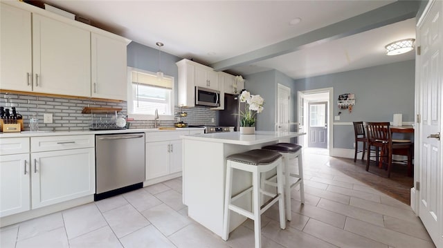 11 Crane St S, Pawtucket, RI 02860 - kitchen with appliances with stainless steel finishes, backsplash, a kitchen island, a kitchen breakfast bar, and a sink
