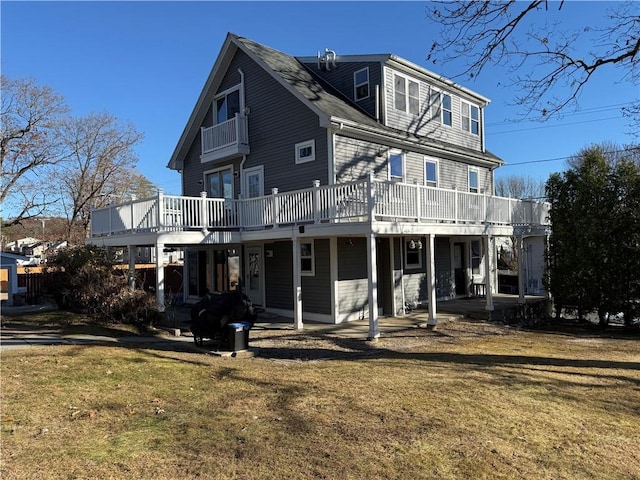 back of property featuring a balcony, a yard, and a deck
