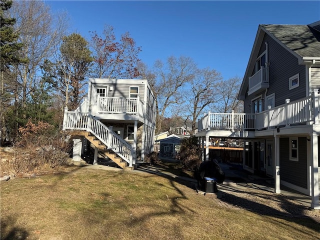 rear view of house featuring a wooden deck, a lawn, and stairway