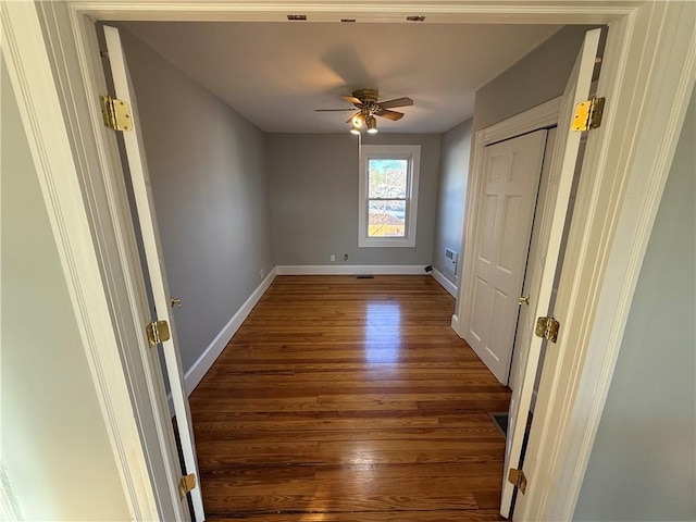 unfurnished bedroom with wood finished floors, baseboards, a closet, and a ceiling fan