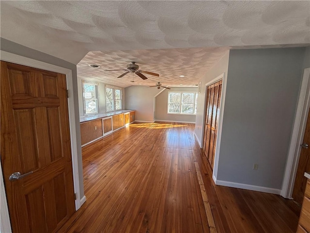 additional living space featuring baseboards, wood-type flooring, a ceiling fan, and a textured ceiling