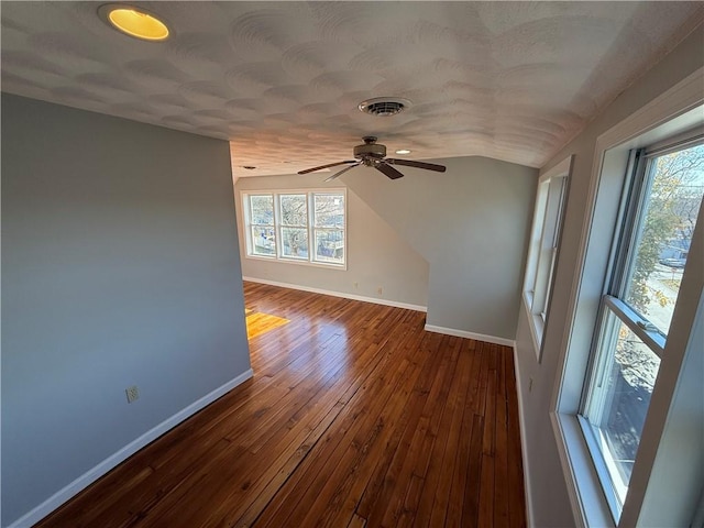 empty room featuring vaulted ceiling, baseboards, plenty of natural light, a ceiling fan, and dark wood-style floors