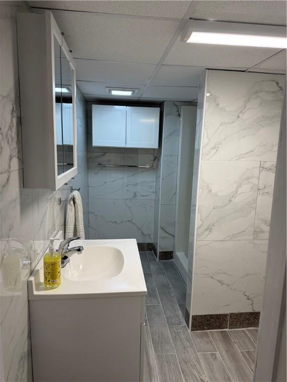 full bathroom with a marble finish shower, vanity, and wood finish floors