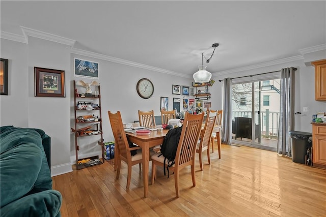 dining area featuring ornamental molding, light wood-style floors, and baseboards