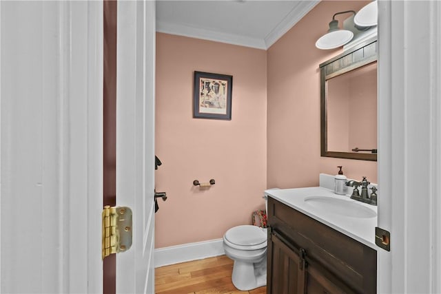 bathroom featuring ornamental molding, wood finished floors, vanity, toilet, and baseboards