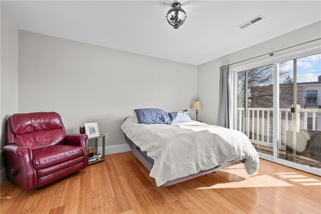 bedroom with access to outside, wood finished floors, and baseboards