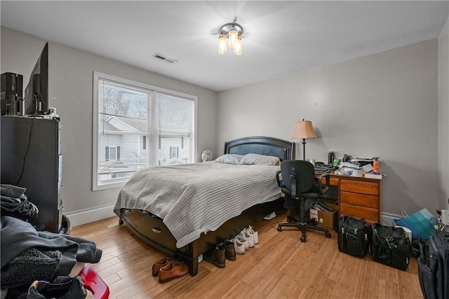 bedroom with wood finished floors, baseboards, and an office area