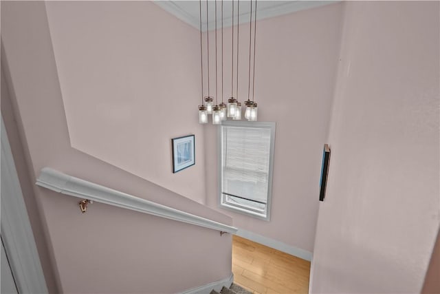 stairway featuring ornamental molding, wood finished floors, and baseboards
