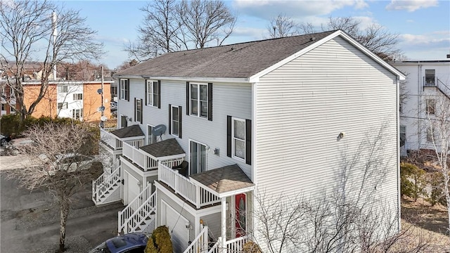 view of side of home with a shingled roof and stairs