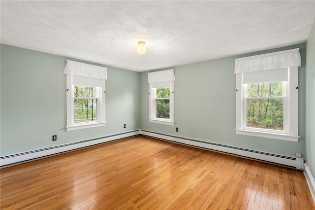 empty room with hardwood / wood-style floors and a baseboard heating unit