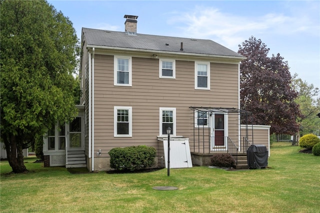 rear view of house with a lawn, a chimney, and a sunroom