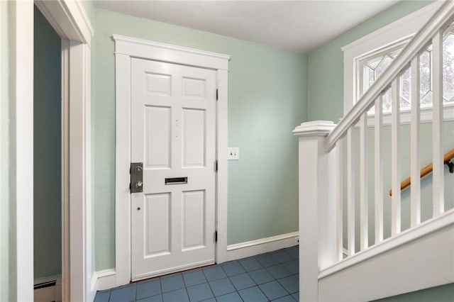 foyer with dark tile patterned floors, stairway, a baseboard radiator, and baseboards